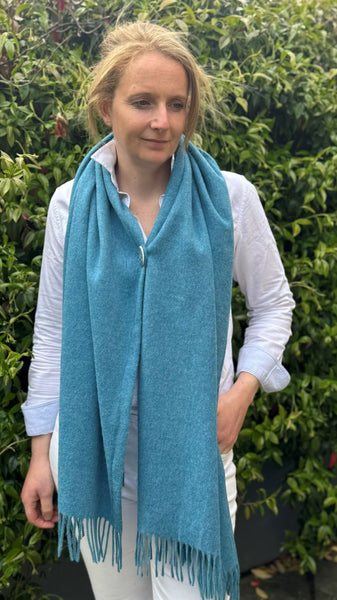ocean blue merino poncho worn as a buttoned scarf